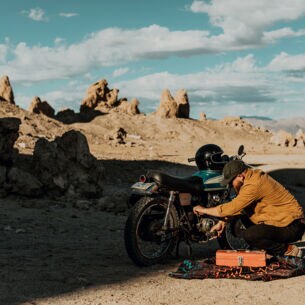 Ein Mann repariert Motorrad in Steinwüste