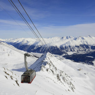 Eine Seilbahn fährt über ein bergiges Skigebiet bei St. Moritz.