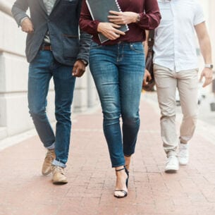 Drei Personen in Jeans gehen auf der Straße