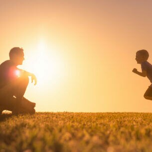 Ein Erwachsener und ein Kind gegen die Sonne fotografiert.