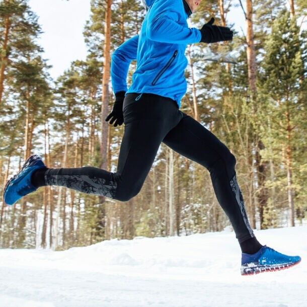 Ein Mann joggt im verschneiten Wald.