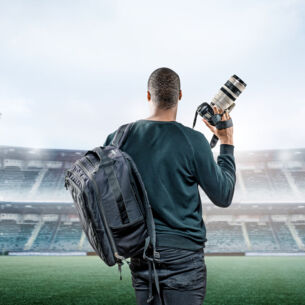 Mann im Stadion mit Kamera und Teleobjektiv