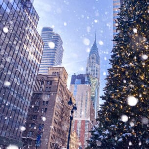 Häuserschlucht in Manhattan mit Blick auf Chrysler Building und Tannenbaum im Vordergrund bei Schneefall