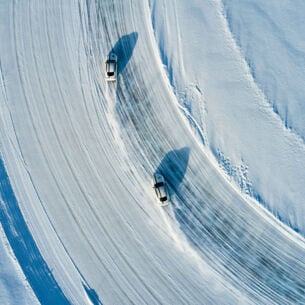 Zwei Sportwagen fahren über ein Eisfeld.