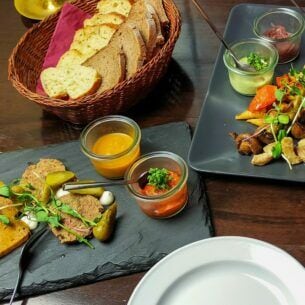 Vegane Tapas mit Dips und Brotkorb, angerichtet auf Servierplatten auf einem gedeckten Tisch