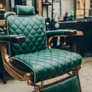 Ein Vintage-Barbersessel mit grünem Lederbezug in einem Barbershop