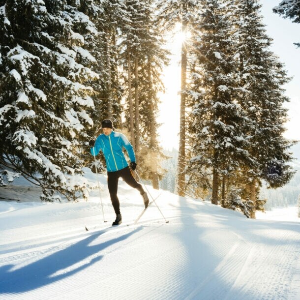 Ein Skilangläufer im klassischen Stil fährt durch den verschneiten Wald