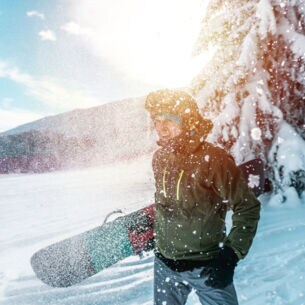 Ein junger Mann mit einem Snowboard unter dem Arm