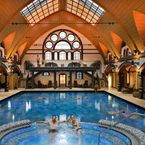 Innenraumansicht einer Schwimmhalle mit Saunalandschaft und Whirlpool im historischen Gebäude mit Kuppeldach