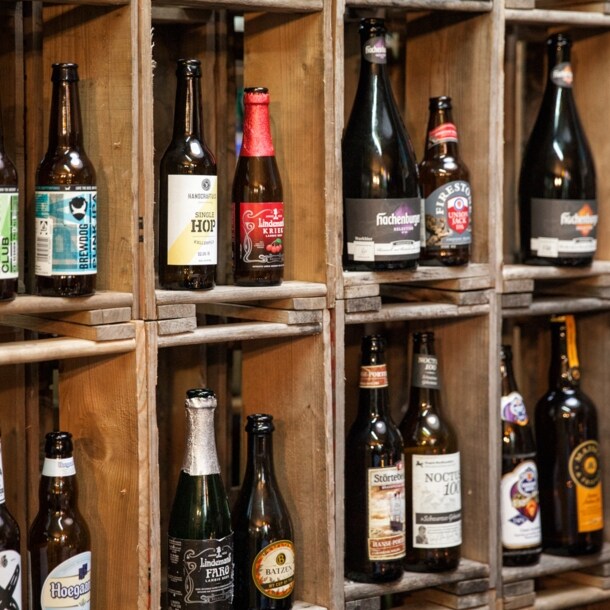 In einem Holzregal stehen verschiedene Bierflaschen