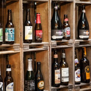 In einem Holzregal stehen verschiedene Bierflaschen