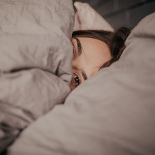Eine Frau liegt unter einer Bettdecke im Bett
