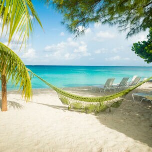 Eine Hängematte hängt am Sandstrand auf Jamaika