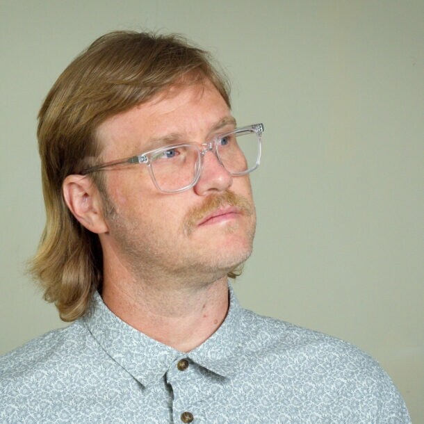 Ein Mann mit einem Mullet-Haarschnitt und Brille