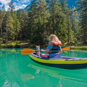 Eine Frau mit einem Hund im Kanu auf einem türkisfarbenen Fluss