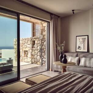 Hell eingerichtetes Hotelzimmer mit Terrasse und Blick aufs Meer
