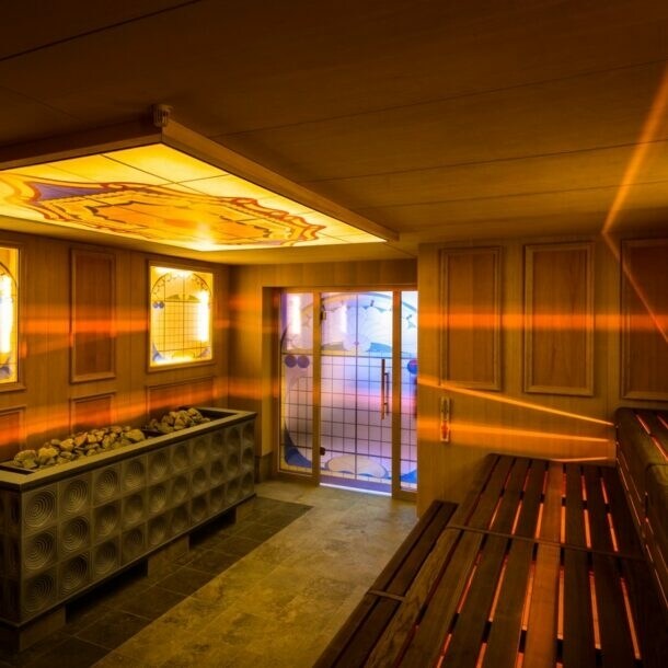 Holzsauna mit gelben, dekorierten Glasplatten, durch die Lichtstrahlen ins Innere dringen