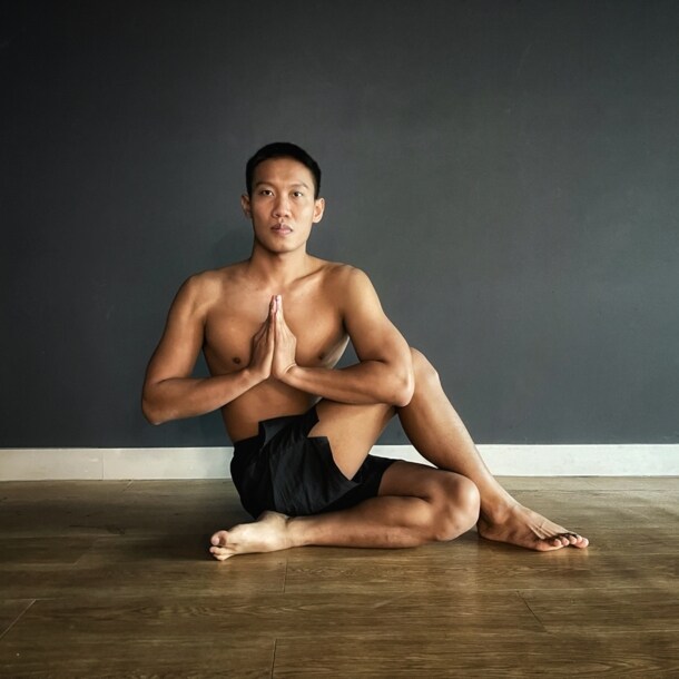 Mann macht Yoga, sitzt im halben Drehsitz