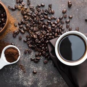Kaffeebohnen, gemahlener Kaffee und eine Tasse Kaffee von oben fotografiert.