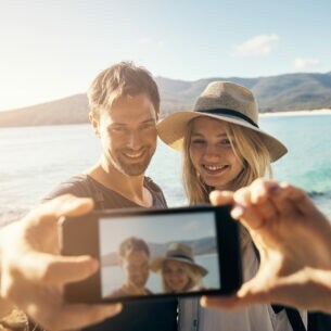 Frau und Mann machen ein Selfie am Strand
