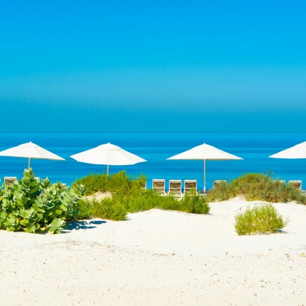 Sandstrand und blaues Meer mit Sonnenliegen und Sonnenschirmen
