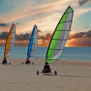 Drei Strandsegler bei Sonnenuntergang.