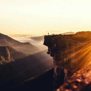 Aussicht auf einen Reisenden, der an einem sonnigen Tag auf einem Felsvorsprung steht.