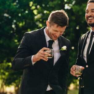 Bräutigam und Trauzeuge trinken und lächeln während der Hochzeitsfeier