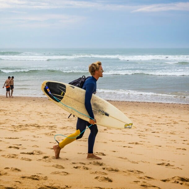 Ein Surfer mit Surfbrett an einem Strand