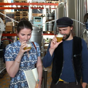 Zwei Personen riechen an gefüllten Biergläsern in einer Brauerei