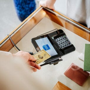 Eine Person zahlt in einer Amex Akzeptanzstelle kontaktlos mit Kreditkarte