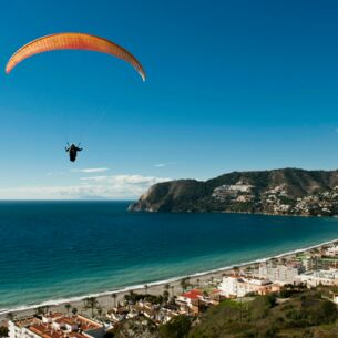 Ein Paraglider schwebt über einer Küstenstadt
