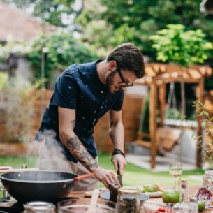 Ein Mann bereitet in einer Outdoorküche ein Gericht zu