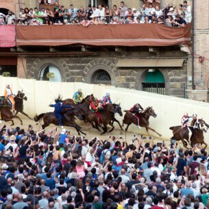 Reiter und Publikum beim Pferderennen Palio di Siena auf dem mittelalterlichen Platz der Stadt