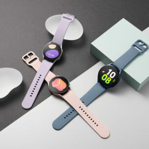 Drei verschiedenfarbige Uhren liegen auf einem grau-weißen Hintergrund