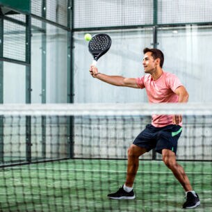 Ein Mann spielt Padel-Tennis in der Halle.