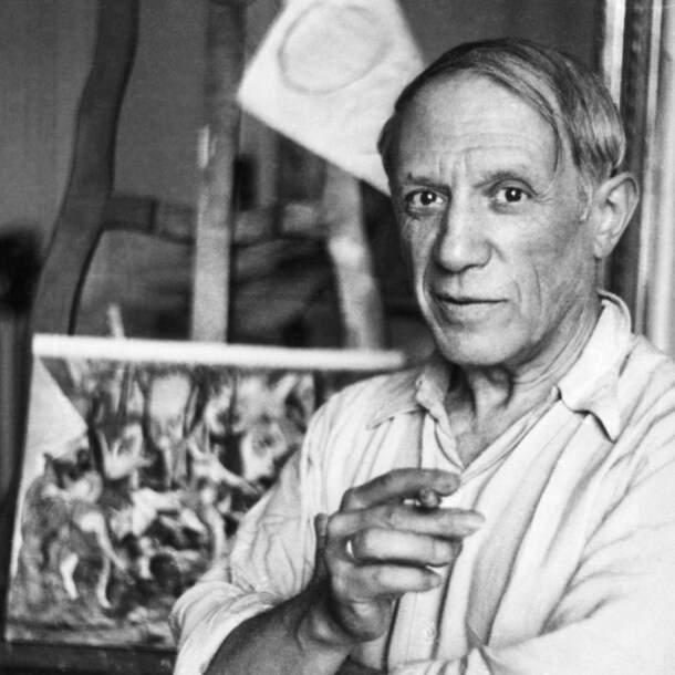 Schwarzweiß-Porträt von Pablo Picasso mit Zigarette in seinem Studio vor einer Staffelei, 1920