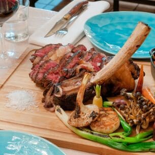 Ein auf einem Brett angerichtetes Steak mit gegrilltem Gemüse auf einem gedeckten Tisch