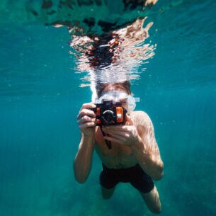 Ein Mann beim Schnorcheln mit einer Unterwasserkamera.