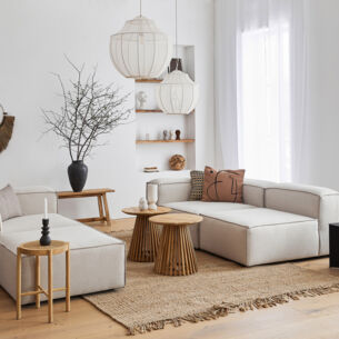 Ein lichtdurchflutetes, modernes Wohnzimmer im skandinavischen Design mit einer kubischen Sitzgruppe aus grauem Stoff und dekorativen Wohnaccessoires