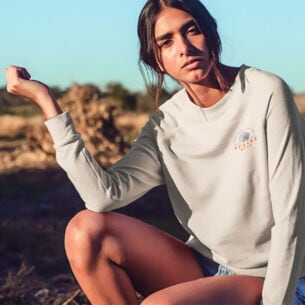 Eine junge Frau posiert in einem hellen Sweatshirt in der Natur