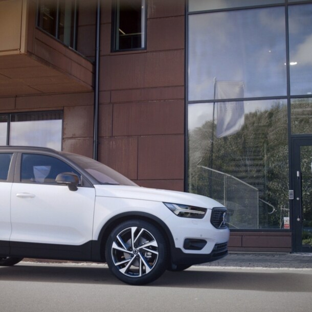 Ein Mann und eine Frau schütteln sich neben einem Auto die Hand