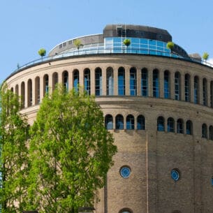 Ein runder, historischer Wasserturm mit moderner Terrasse
