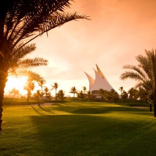 Ein gepflegter Golfplatz mit Palmen im Abendlicht