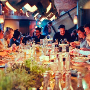 Eine große gesellige Menschengruppe sitzt an einem Tisch und isst zusammen.