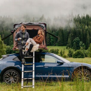 Eine Frau und ein Mann an einem Auto mit Dachzelt