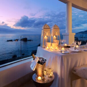 Große Terrasse einer Hotelsuite am Meer mit einem elegant gedeckten Tisch in der Abenddämmerung