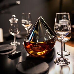 Eine Flasche Bowmore ARC-52 aus der Kooperation mit Aston Martin steht auf einem Tisch mit speziellen Whisky-Gläsern