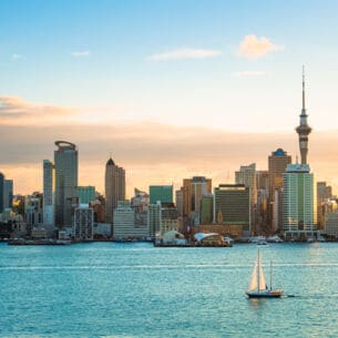 Stadtpanorama von Auckland am Wasser mit einem Segelboot im Vordergrund