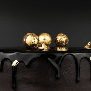 Schokoladentorte, verziert mit drei Kugeln, die mit Blattgold ummantelt sind